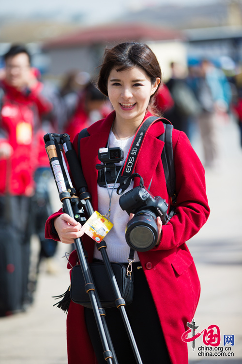 2016年兩會，人民大會大堂前，一位笑容燦爛的紅衣女記者正步入大會堂。中國網 鄭亮 攝